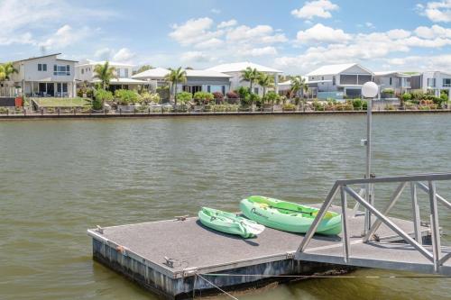 a dock with two boats on the water at Spacious waterfront home with pontoon, pool, BBQ in Kawana Waters