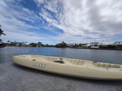 Un kayak blanco sentado en un muelle en el agua. en Spacious waterfront home with pontoon, pool, BBQ, en Kawana Waters
