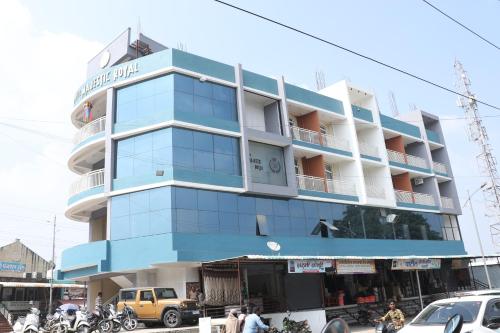 a blue building with cars parked in front of it at Hotel Majestic Royal, Akkalkot in Akalkot