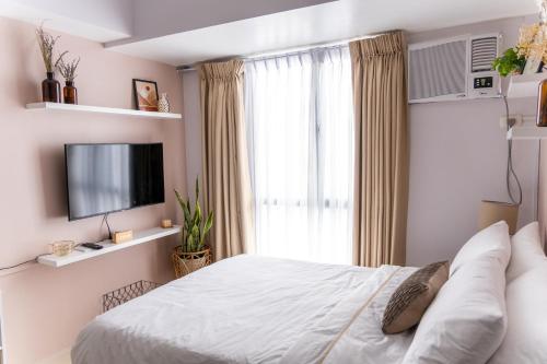 une chambre avec un lit blanc et une télévision dans l'établissement Cozy Nest Tagaytay, à Tagaytay