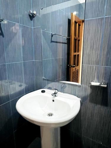 un bagno con un lavandino bianco e uno specchio di GoBeyond - Serra T2 a Porto Novo