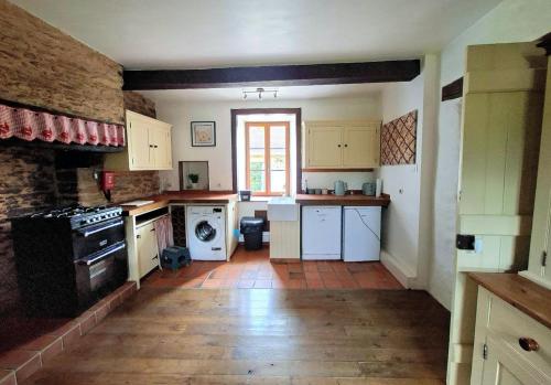 a kitchen with white appliances and a brick wall at Birdsong in Saint-Éloy-les-Tuileries