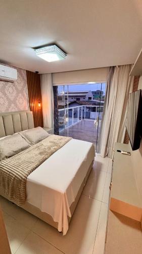a bedroom with a large bed and a balcony at Casa 51 Piscina 3 suites prox Beto Carrero in Penha