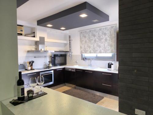 a kitchen with black cabinets and white appliances at Blue Tulip - Strovolos in Kato Lakatamia