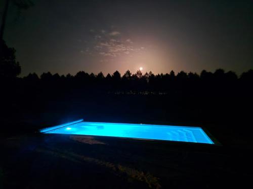 ein nachts beleuchtetes Schwimmbecken auf einem Feld in der Unterkunft Calme et paisible maison au milieu de la foret in Arx