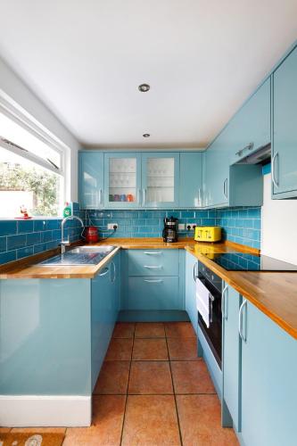 a blue kitchen with blue cabinets and a sink at Heart of Brighton - Stylish - Victorian Terrace in Brighton & Hove
