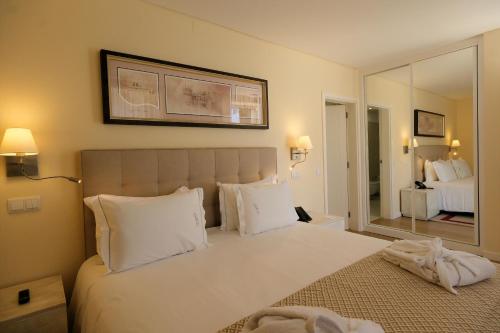 a bedroom with a large white bed with a large mirror at Quinta da Maquia Hotel in Sintra