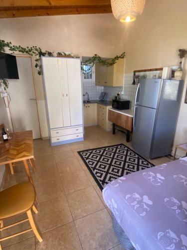 a kitchen with a refrigerator and a table and a table at Olive Grove Cottage Guest house in Kouka