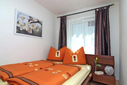 um quarto com 2 camas com almofadas laranja e uma janela em Haus Hillinger em Salzburgo