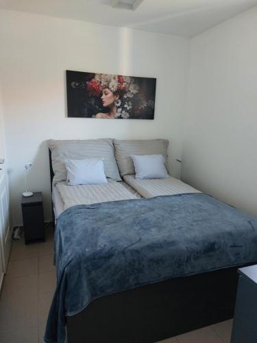 a bed in a bedroom with a painting on the wall at Virágos Lakás in Győr