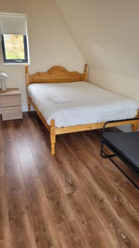 a bedroom with a bed and a wooden floor at Machaire Rabhartaigh Glamping in Mín Lárach