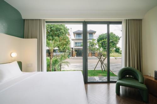 a bedroom with a bed and a chair and a window at TRON Villa - Regal Victoria Luxury BT9-09 in Dien Ban