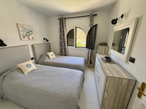 a bedroom with two beds and a dresser and a mirror at Miami Beach in Mogán
