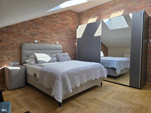 een slaapkamer met een bed en een bakstenen muur bij Apartament Pałac Tryllingów in Białystok