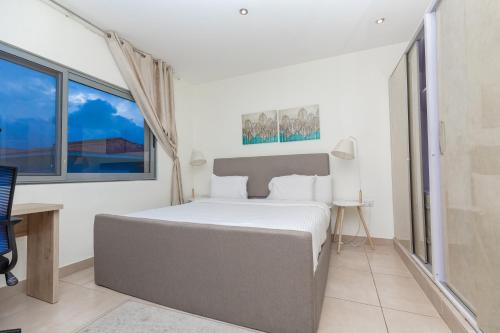 Un dormitorio con una cama grande en una habitación con ventanas. en CasaNova Airport Suites, en Accra