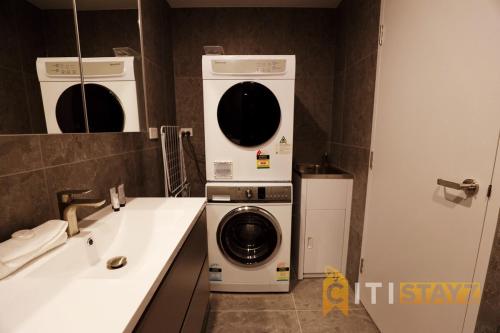 een badkamer met een wasmachine en droger naast een wastafel bij Red Rose Retreat - 1bd 1bth 1CarSp Apt in Lyons