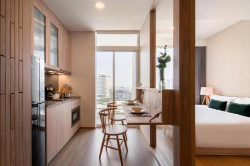 a bedroom with a bed and a kitchen with a table at Urban Oasis BTS Ekkamai in Khlong Toei
