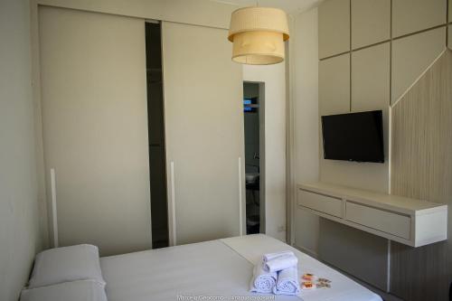 Una pequeña habitación con una cama y un televisor. en Suítes Alto Itamambuca, en Ubatuba