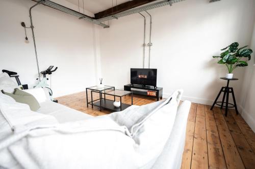 a living room with white furniture and a tv at The Loft - Luxe City Centre Penthouse Apartment in Norwich