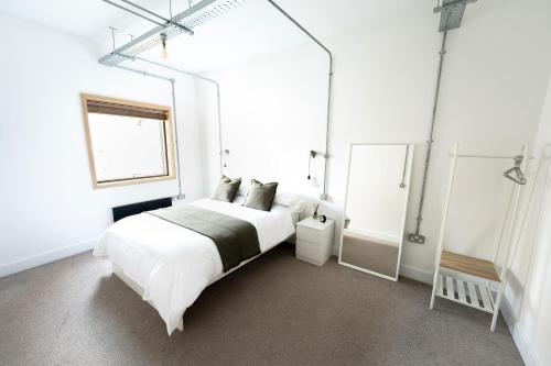 a white bedroom with a large bed and a mirror at The Loft - Luxe City Centre Penthouse Apartment in Norwich