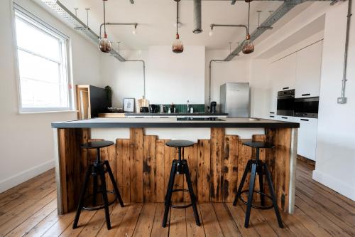 a kitchen with a large island with bar stools at The Loft - Luxe City Centre Penthouse Apartment in Norwich