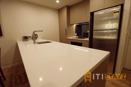 eine weiße Küche mit Spüle und Kühlschrank in der Unterkunft Ruby Red, 1Bd 1Bth Apt - Woden CBD in Phillip