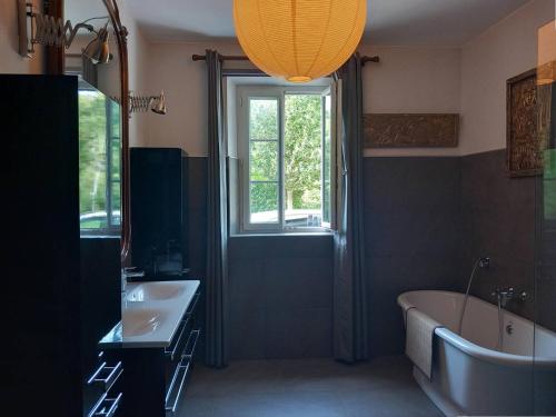 une salle de bain avec une baignoire, un lavabo et une fenêtre dans l'établissement Maison idéale à Mendionde pour 8 personnes, avec grand jardin et équipements modernes - FR-1-495-104, à Mendionde