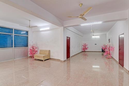 a living room with a ceiling fan and pink flowers at Hotel O Mahadevi Lawn in Lucknow