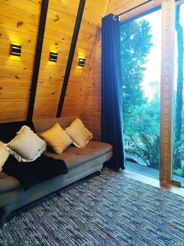 a couch in a room with a large window at Chalé Passione in Gramado