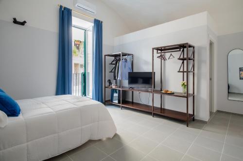 ナポリにあるPlebiscito Luxury Roomsの白いベッドとテレビのある寝室