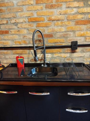 a kitchen counter with a sink and a brick wall at Chalé Passione in Gramado