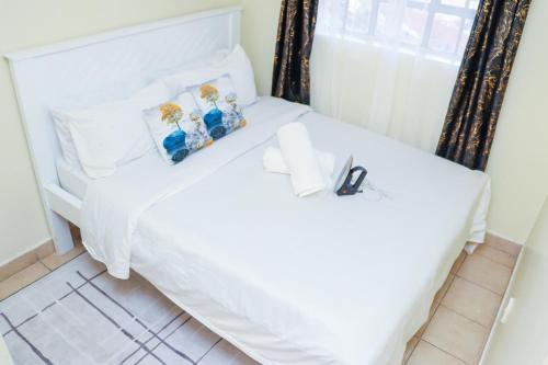 a bedroom with a white bed with a window at Solace Park Apartments in Gatunga