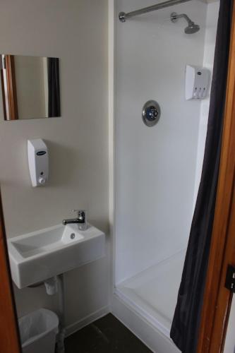 a white bathroom with a sink and a shower at Three Furlongs Bar-Grill-Hotel in Kaiwaka