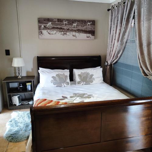 a bedroom with a bed with white sheets and pillows at Quiet Getaway in Bloemfontein