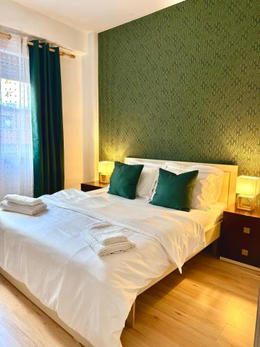 a bedroom with a large white bed with green walls at N&N City Nest Apartment in Tirane