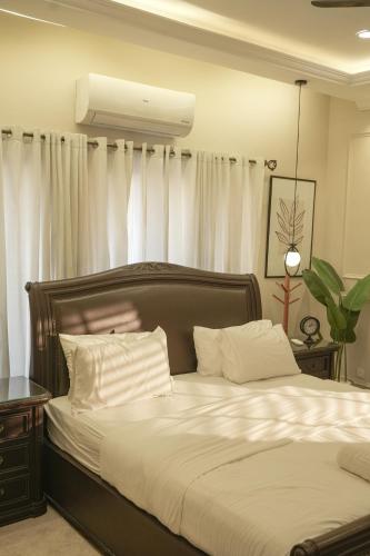 a bedroom with a large bed with white curtains at Fior Residence 2BHK in Rawalpindi