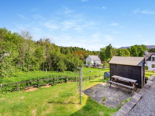 a wooden shed with a bench in a field at Lockview Upper Flat in Fort Augustus