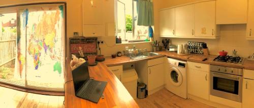 a kitchen with a table and a laptop on a counter at Quiet room in London