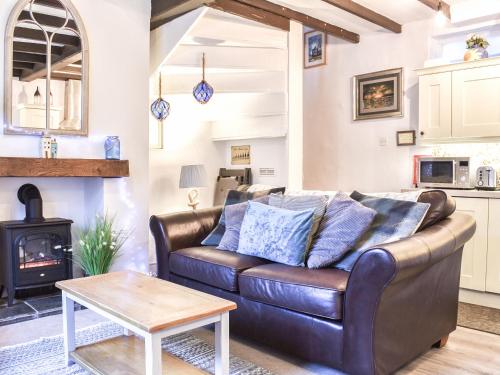 a living room with a leather couch and a stove at Sea Dog Cottage - Uk42479 in Whitby