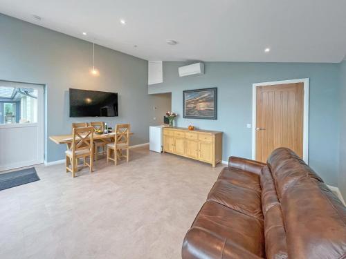 sala de estar con sofá de cuero y comedor en Grey Rocks Apartment, en Kippford