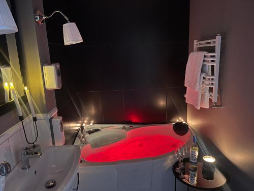 a red bath tub in a bathroom with a sink at EUROPA22 Apartament RELAKS z JACUZZI w samym sercu miasta Prestiżowe osiedle z widokiem na park i staw z fontannami Szybkie i Łatwe Zameldowanie in Tomaszów Mazowiecki