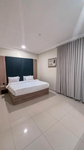 a bedroom with a large bed with a blue headboard at زهرة القصيم شقق مفروشة in Buraydah