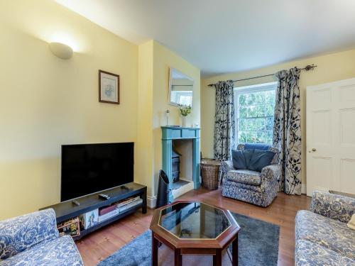 a living room with a tv and a couch and a table at Primula House in Sticklepath