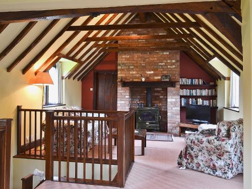 a living room with a stone fireplace and a staircase at Mill Cottage in Mathon