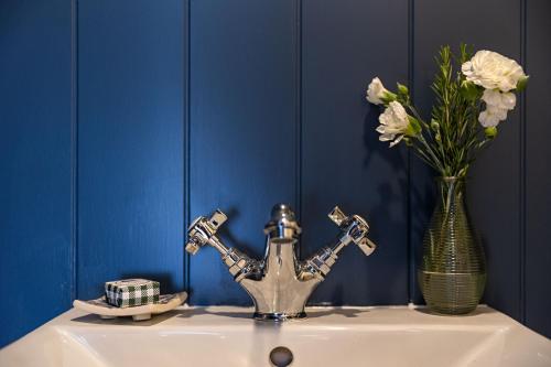 a bathroom sink with a vase of flowers and a sink at Da Vinci's Den in North Tawton