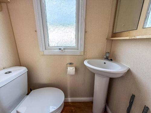 Un baño con inodoro, lavabo y ventana. en 6 Berth Caravan Nearby Hunstanton Beach Front In Norfolk Ref 13019L, en Hunstanton