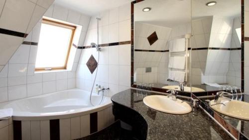 a bathroom with two sinks and a tub and a mirror at Aparthotel Astro - Nichtraucherhotel in Stuttgart