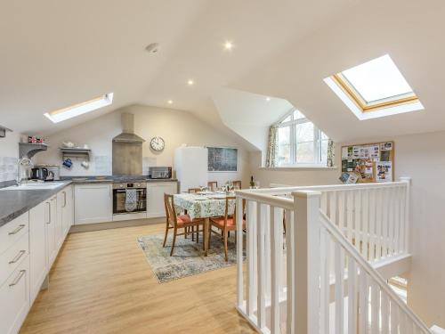 a kitchen and dining room with a table and a kitchen with white cabinets at The Stables At Wells-In-The-Field Farm in Whitchurch