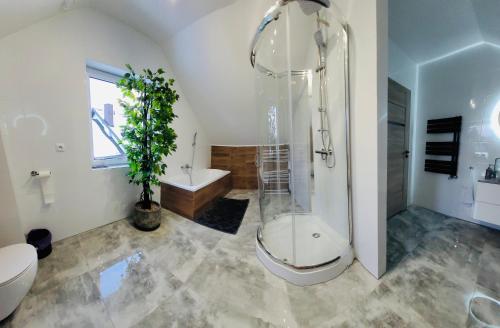 Un baño con ducha, inodoro y bañera. en Apartament POD STRZECHĄ, en Bolmin