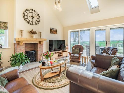 a living room with leather furniture and a fireplace at Lizzie's Cottage in Skendleby